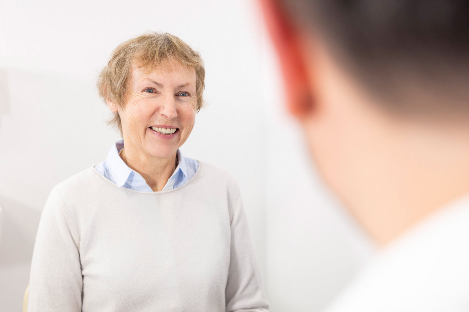 Ältere Dame lächelt während Beratungsgespräch in einer Arztpraxis